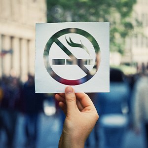 A hand holding a ‘No Smoking’ sticker
