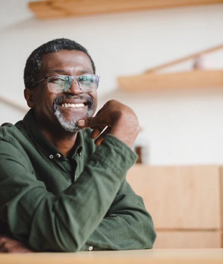 a man in glasses smiling while sitting down